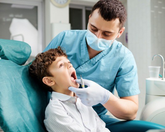 Dentist examining child's smile during preventive dentistry visit