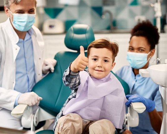 Little boy in dental treatment chair, making thumbs up gesture