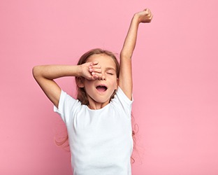 Yawning girl standing against pink background