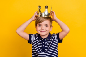 Little boy putting a crown on his head