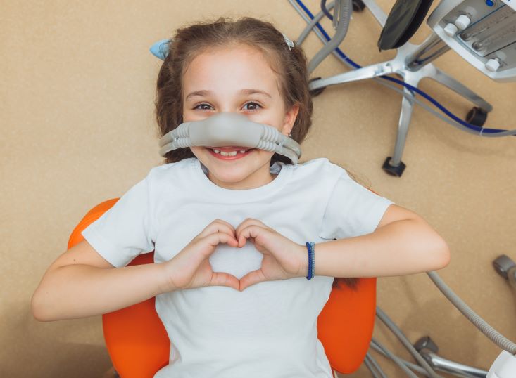 A little girl in a dentist's chair undergoing nitrous oxide sedation dentistry.